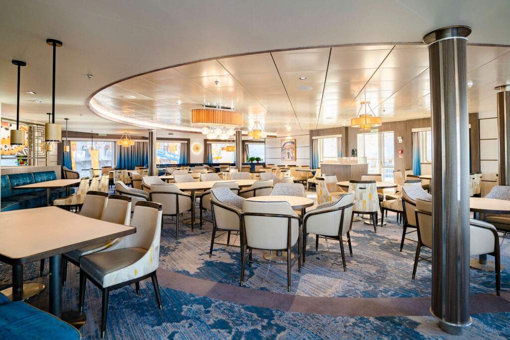 An eating area on a cruise ship with tables and chairs.