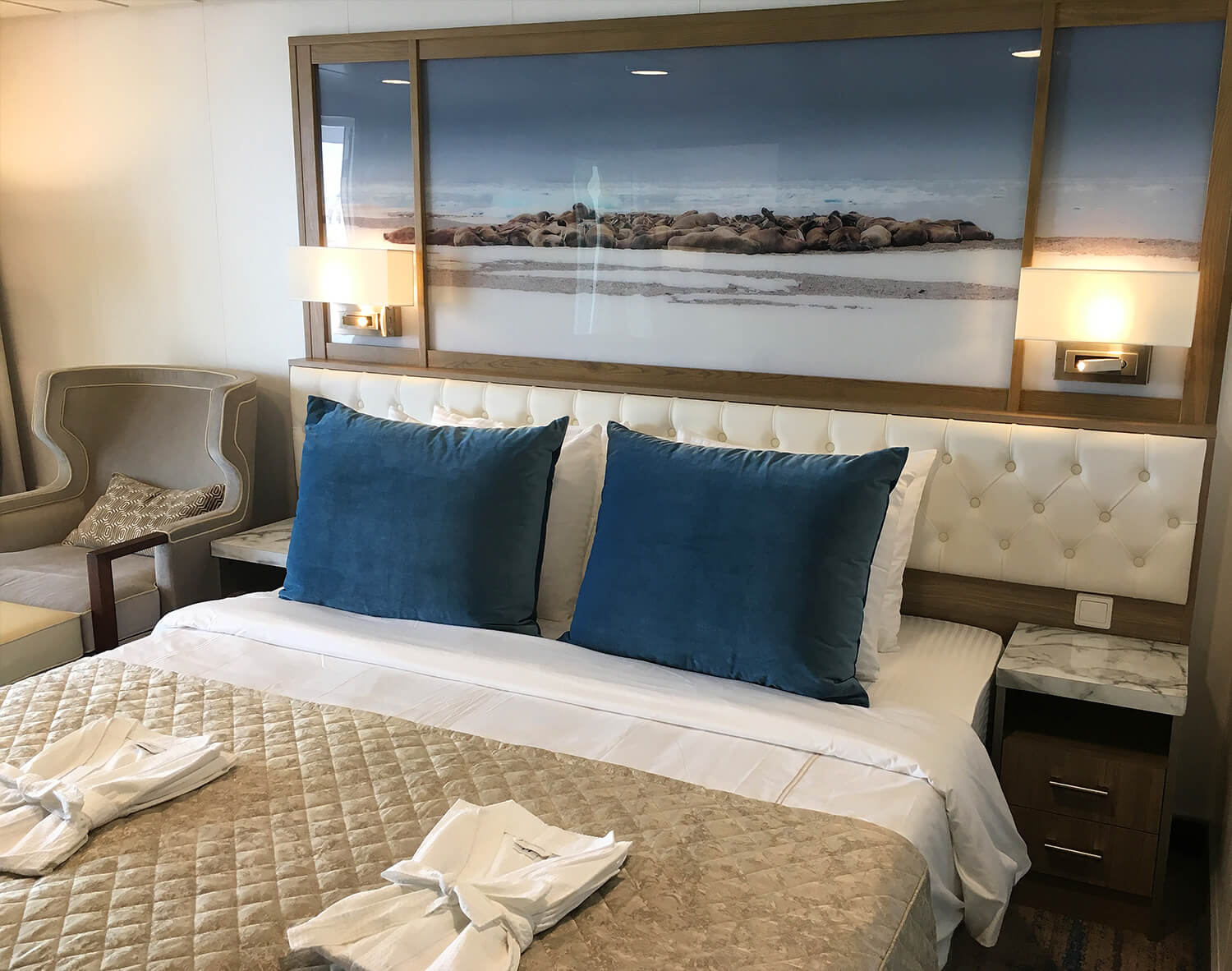 A bed with mirror and side tables in a cruise ship cabin